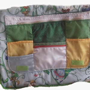May include: A green and white patchwork fabric bag with a zippered pocket and multiple smaller pockets. The bag features a whimsical design of a girl climbing a beanstalk.
