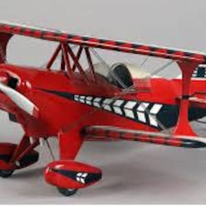 Op de afbeelding: Een rood en zwart model van een dubbeldekker met een witte propeller. Het vliegtuig heeft een opvallend zwart-wit gestreept ontwerp op de vleugels en romp.