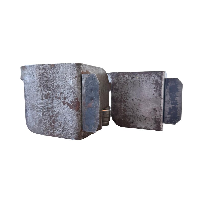 May include: A weathered, antique metal lock with a rectangular body and a hinged door. The lock is a dull gray color with signs of rust and wear, suggesting age and use. The design is simple and functional.