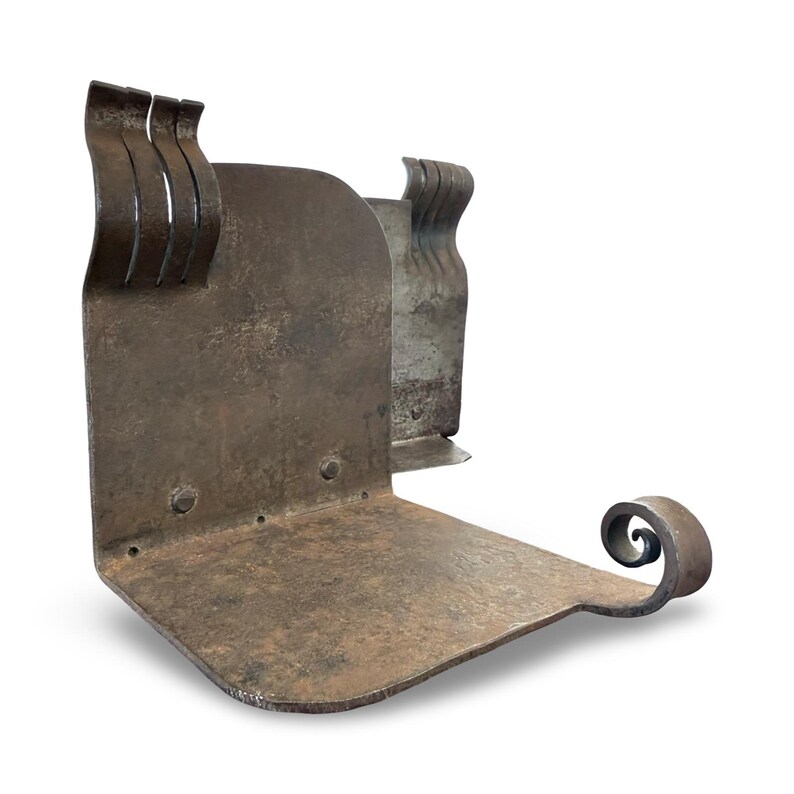 May include: A weathered, L-shaped metal bookend with a rustic, industrial aesthetic. The bookend features a flat base, a vertical support with three curved accents, and a decorative scroll detail. The metal has a dark, aged finish.