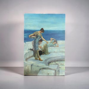 Op de afbeelding: Een ingelijst schilderij toont drie vrouwen in klassieke kleding bij een waterpartij. Eén vrouw houdt een mand vast, een andere ligt en een derde zit. Het kunstwerk heeft een blauw en groen kleurenpalet, met de nadruk op de figuren en hun omgeving.