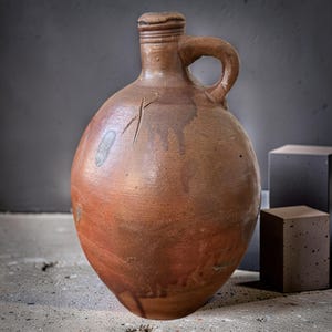 Antique 19th-century rustic stoneware jug with a round body, a narrow neck, and a sturdy handle.