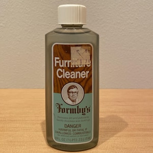 May include: A bottle of Formby's Furniture Cleaner. The label features the product name, a portrait of a man, and warnings. The bottle is gray with a white cap and contains 8 fl oz (1/2 pt) or 0.23 liters.