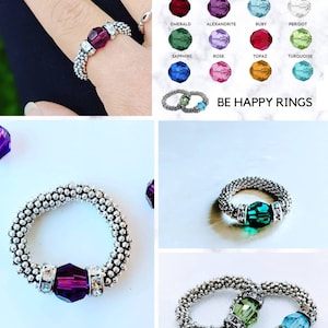 May include: A silver ring with a purple Swarovski crystal. The ring is made of small silver beads and has a simple design. The ring is shown on a white background with a purple crystal.