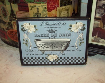 Op de afbeelding: Een blauw en wit bord met een zwarte rand en een geruite rand. Het bord toont een vintage illustratie van een badkuip met een bloemenontwerp en de tekst "J. Blondel & Co. Suc. 33 Rue des Jeûneurs. 33 SALLE DE BAIN T&T A mon zivilateur de Loca au Péron qui a si souvent 201 forces."