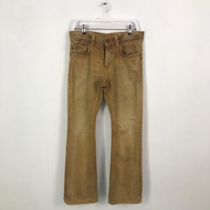 May include: A pair of brown, wide-leg jeans with a faded look. The jeans have a straight leg and a slight flare at the bottom.