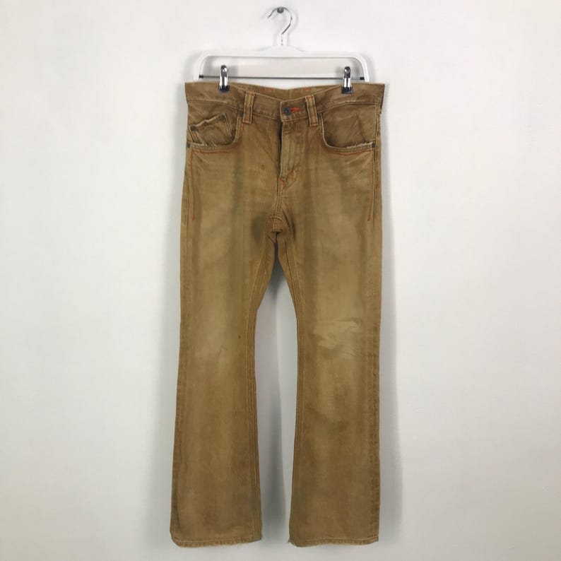 May include: A pair of brown, wide-leg jeans with a faded look. The jeans have a straight leg and a slight flare at the bottom.