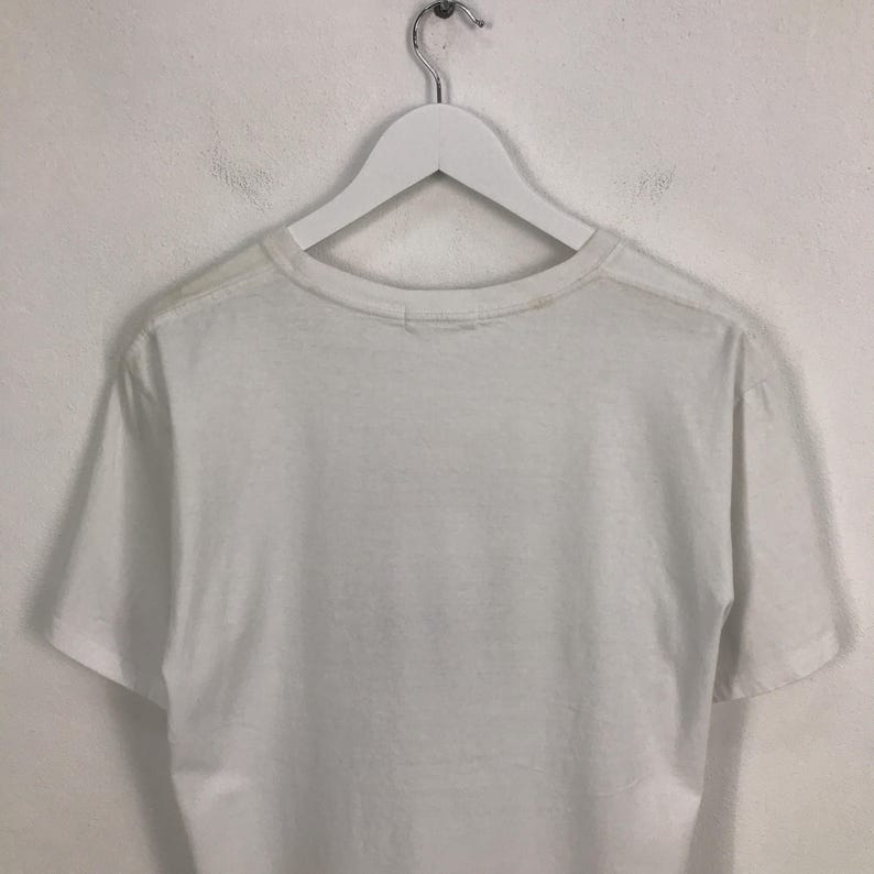 May include: White t-shirt with a crew neck and short sleeves.