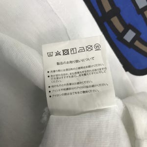 May include: White care label with black text and symbols. The text reads "Product care instructions". The symbols include a washing machine icon with a 40 degree symbol, a hand washing icon, a bleach icon with a cross through it, a tumble dryer icon with a circle through it, an iron icon with a dot, and a dry clean icon with a circle through it and a W.