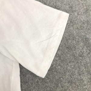 May include: Close-up of the white cotton fabric of a t-shirt sleeve. The fabric is smooth and wrinkle-free.