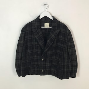May include: A dark grey and black checked blazer with two buttons, hanging on a white hanger. The jacket has a classic collar and a tailored fit. The fabric appears to be a wool blend.