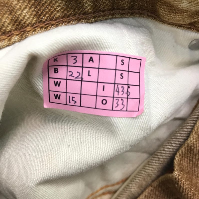 May include: A pink and white label with the text "K 3 A S B 22 L S W 15 I 43.6 O 33" printed on it.