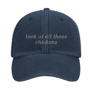 May include: A dark blue denim baseball cap with the text "look at all those chickens" embroidered in white on the front.