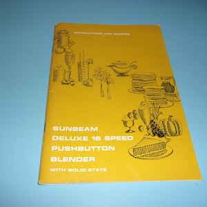 May include: A vintage yellow cookbook titled "Instructions and Recipes" for a Sunbeam Deluxe 16 Speed Pushbutton Blender. The cover features black illustrations of food and drinks, including a blender, pancakes, and a slice of pie.