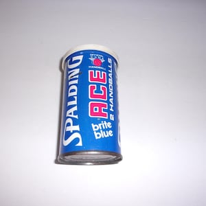 May include: A blue and white can of Spalding Ace Handballs. The can has the text "Spalding Ace 2 Handballs Brite Blue" on it.