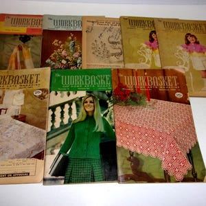 May include: A collection of vintage "Workbasket" magazines. The covers feature images of crafts, fashion, and home decor. The magazines have a retro aesthetic, with faded colors and classic fonts. The magazines are from different months and years.