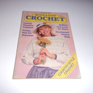 May include: A vintage July/August 1987 issue of "Quick & Easy Crochet" magazine. The cover features a woman wearing a white crocheted sweater and hat, holding yellow flowers. Text includes "Lovely Country Fashion" and "Pretty Hat for Summer".