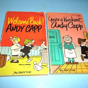 May include: Two vintage Andy Capp comic books. The first book has a red cover with the title "Welcome Back!" and the second book has a pink cover with the title "You're a Knockout!". Both books feature cartoon illustrations and the author's name, "By SMYTHE."