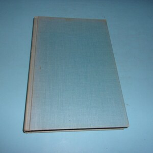 May include: A closed book with a light blue cover and a gray spine. The cover has a textured appearance. The book is set against a light blue background.