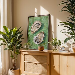 Op de afbeelding: Een houten kast met twee deuren en twee laden. De kast is lichtbruin en heeft een geweven rotanfront op de onderste lade. De kast is versierd met twee planten in potten, een ingelijst schilderij van twee oesters op een groene achtergrond en een kleine klok.