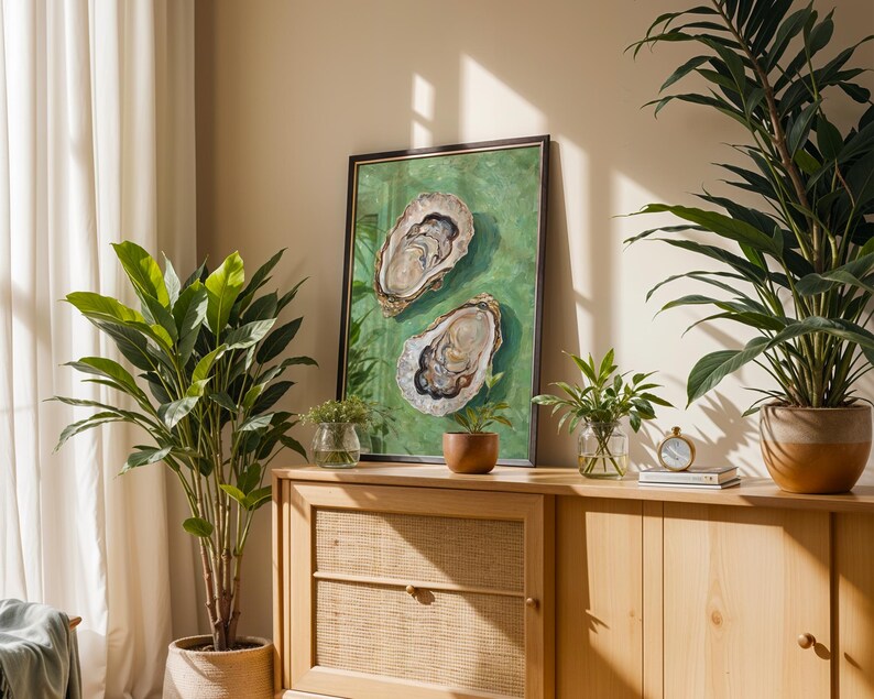 Op de afbeelding: Een houten kast met twee deuren en twee laden. De kast is lichtbruin en heeft een geweven rotanfront op de onderste lade. De kast is versierd met twee planten in potten, een ingelijst schilderij van twee oesters op een groene achtergrond en een kleine klok.