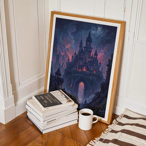 May include: A framed print depicting a gothic castle under a dramatic sky. The artwork is propped against a wall, beside a stack of books and a coffee mug. The frame is a light wood colour.
