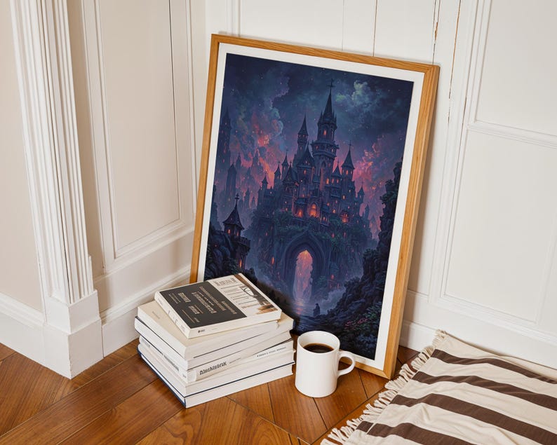 May include: A framed print depicting a gothic castle under a dramatic sky. The artwork is propped against a wall, beside a stack of books and a coffee mug. The frame is a light wood colour.