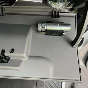 May include: A silver metal wrench with a black plastic handle is attached to the inside of a car door. The wrench is labeled "MADE IN AMERICA".