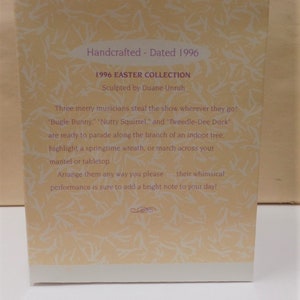 Puede incluir: Una tarjeta con fondo amarillo claro y texto blanco. El texto dice "Handcrafted - Dated 1996", "1996 Easter Collection", "Sculpted by Duane Unruh", "Three merry musicians steal the show wherever they go!" "Bugle Bunny", "Nutty Squirrel", and "Tweedle-Dee Duck" are ready to parade along the branch of an indoor tree, highlight a springtime wreath, or march across your mantel or tabletop. Arrange them any way you please - their whimsical performance is sure to add a bright note to your day!"