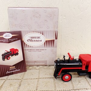 May include: A red and black toy locomotive with a red cab and a black boiler. The toy is a replica of a 1941 Keystone Locomotive and is part of the Kiddie Car Classics Sidewalk Cruisers Collection.