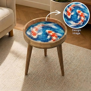 Op de afbeelding: Ronde houten bijzettafel met drie poten. Het tafelblad heeft een blauw en wit ontwerp met twee koi-karpers. De tafel is een decoratief accent. De diameter van de tafel is ongeveer 40 cm.