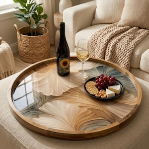May include: A round wooden serving tray with a decorative floral design in shades of beige, brown, and blue. The tray holds a bottle of wine, a glass of wine, and a plate of snacks. The tray is approximately 20 inches in diameter.