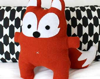 May include: A red fox plush toy with white felt accents for the ears, eyes, and nose. The toy has a simple, cartoon-like design.