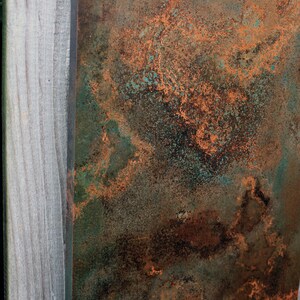 May include: A close-up of a textured metal surface with a mix of brown, green, and orange hues. The surface has a mottled, aged appearance, resembling oxidized copper or bronze.