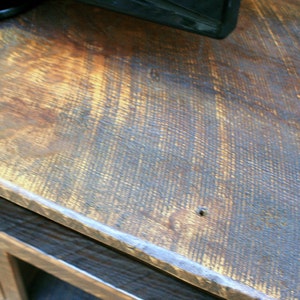May include: Close-up of a dark brown wooden surface with a light brown stain. The surface has a rough, textured grain and a slight sheen.