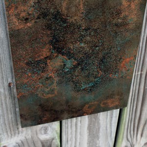 May include: A close-up of a textured metal sheet with a mottled green and copper finish. The surface has a rustic, aged look.