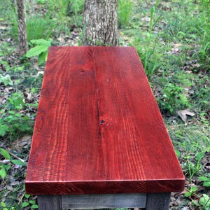 May include: A rustic wooden table top with a rich red stain. The table top is made of reclaimed wood and has a natural, distressed look.