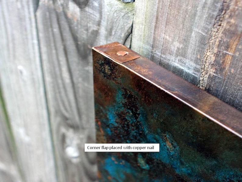 May include: A close-up of a corner flap placed with a copper nail. The flap is made of metal and has a rustic, aged look with a blue-green patina.