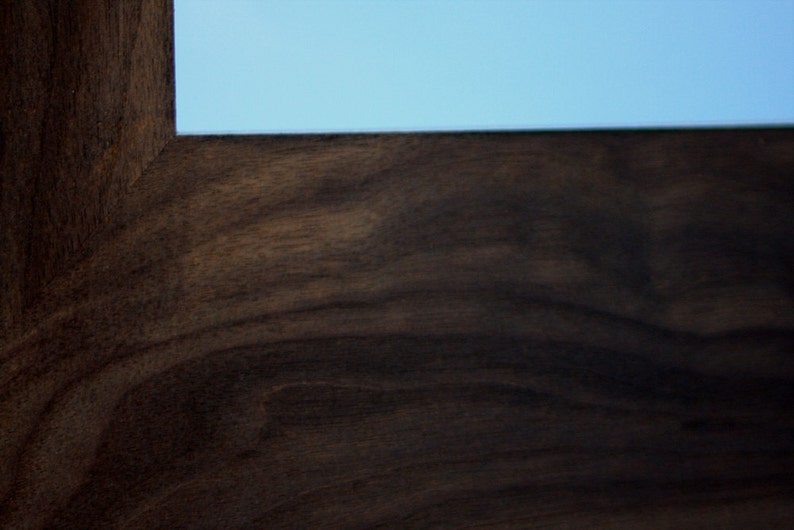 May include: Close-up of a dark brown wood grain surface. The wood has a rich, dark brown color with a natural wood grain pattern.