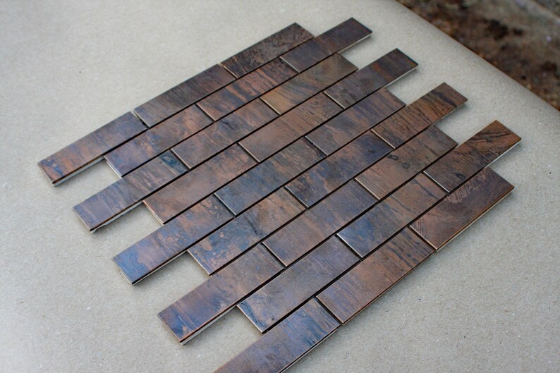 May include: A sheet of copper tile with a brushed finish. The tiles are arranged in a herringbone pattern.