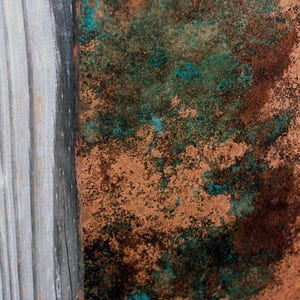May include: Close-up of a weathered wooden surface with a section of the wood painted in shades of brown, green, and blue. The painted section has a mottled, textured appearance.