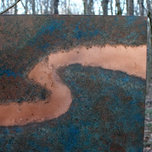 May include: A close-up of a copper metal sheet with a blue and green patina. The copper has a smooth, polished surface and a unique, abstract design.