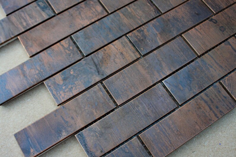 May include: A close-up of a copper metal tile sheet with a brushed finish. The tiles are arranged in a brick pattern and have a dark brown and blue colour.