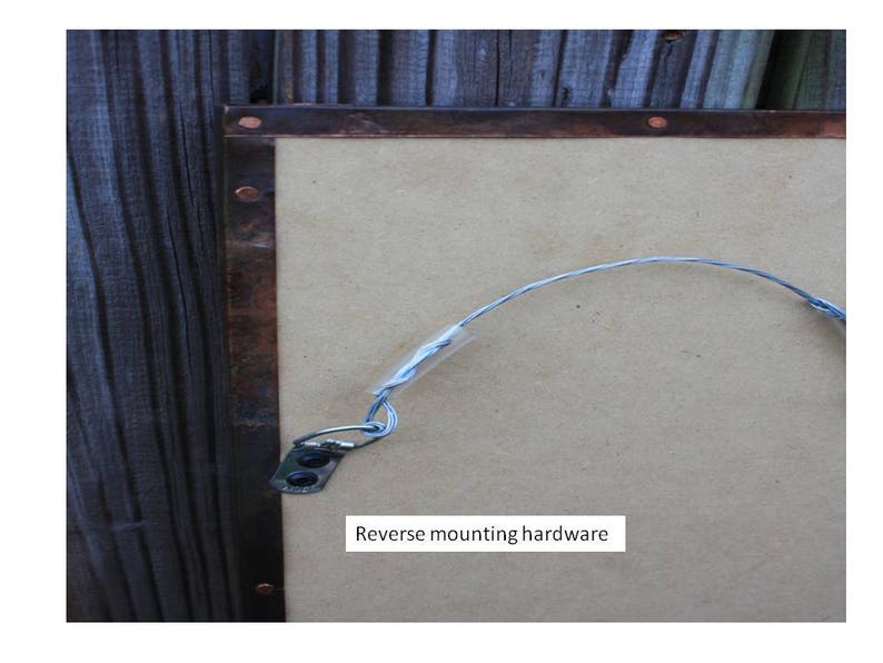 May include: A close-up of the back of a copper framed mirror with a wire hanging system. The text "Reverse mounting hardware" is visible on the mirror.