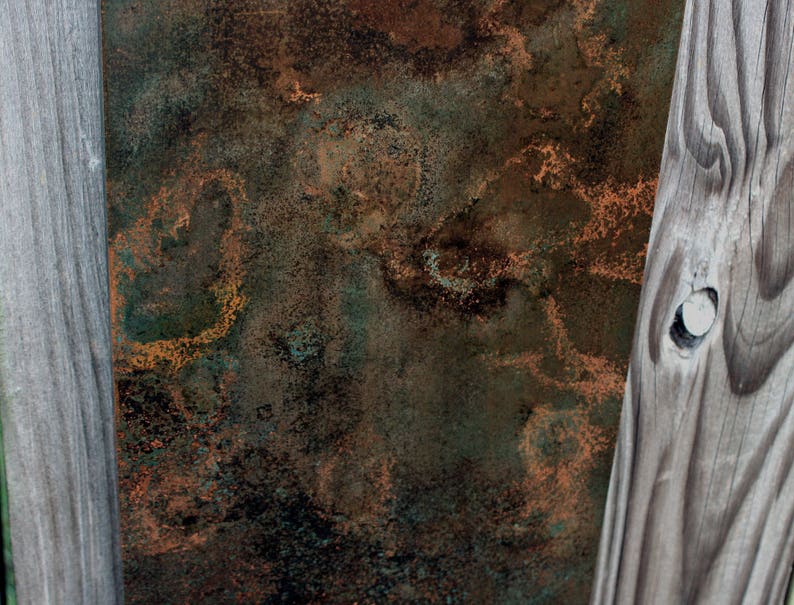 May include: A close-up of a weathered wooden surface with a rusty metal panel behind it. The wood has a natural grain pattern and is painted a light gray color. The metal panel has a mottled brown and green patina with hints of orange.