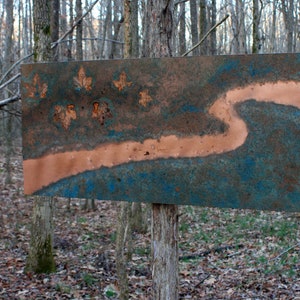 May include: A copper and blue metal wall art piece with a copper river design and leaf accents.
