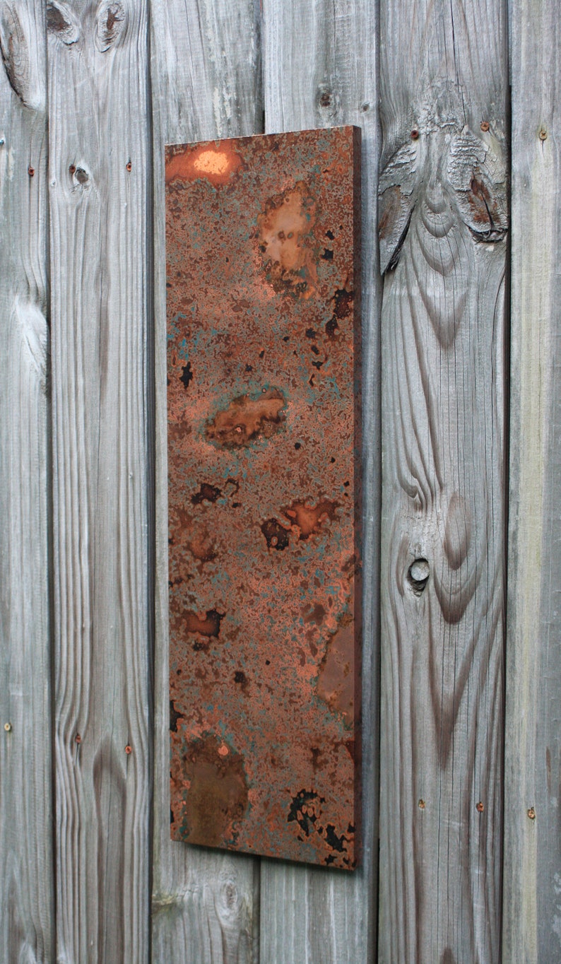 May include: A rectangular metal panel with a rusty, mottled surface. The panel is a mix of orange, brown, and green hues, with a distressed, aged look.
