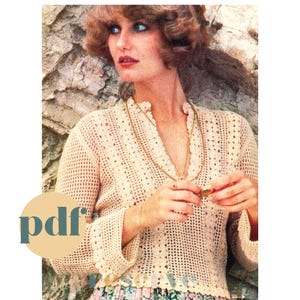 Peut inclure: Un haut en crochet avec un motif ajouré délicat de couleur crème. Le haut a un col en V et des manches longues. Le mannequin porte un collier en chaîne dorée et une bague à son doigt. L'image comprend le texte "pdf" dans un cercle.
