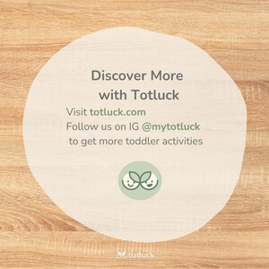 May include: A white circle with rounded edges on a woodgrain background. The text "Discover More with Totluck" is in black text. Below the text is "Visit totluck.com" and "Follow us on IG @mytotluck to get more toddler activities". The Totluck logo is a green leaf with two smiling faces.