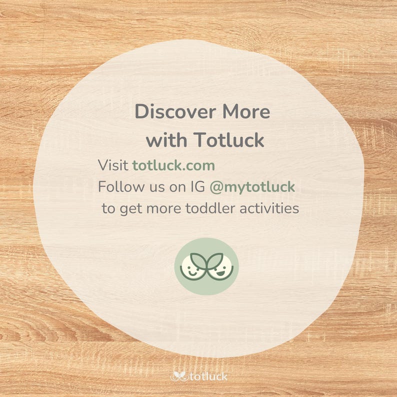 May include: A white circle with rounded edges on a woodgrain background. The text "Discover More with Totluck" is in black text. Below the text is "Visit totluck.com" and "Follow us on IG @mytotluck to get more toddler activities". The Totluck logo is a green leaf with two smiling faces.